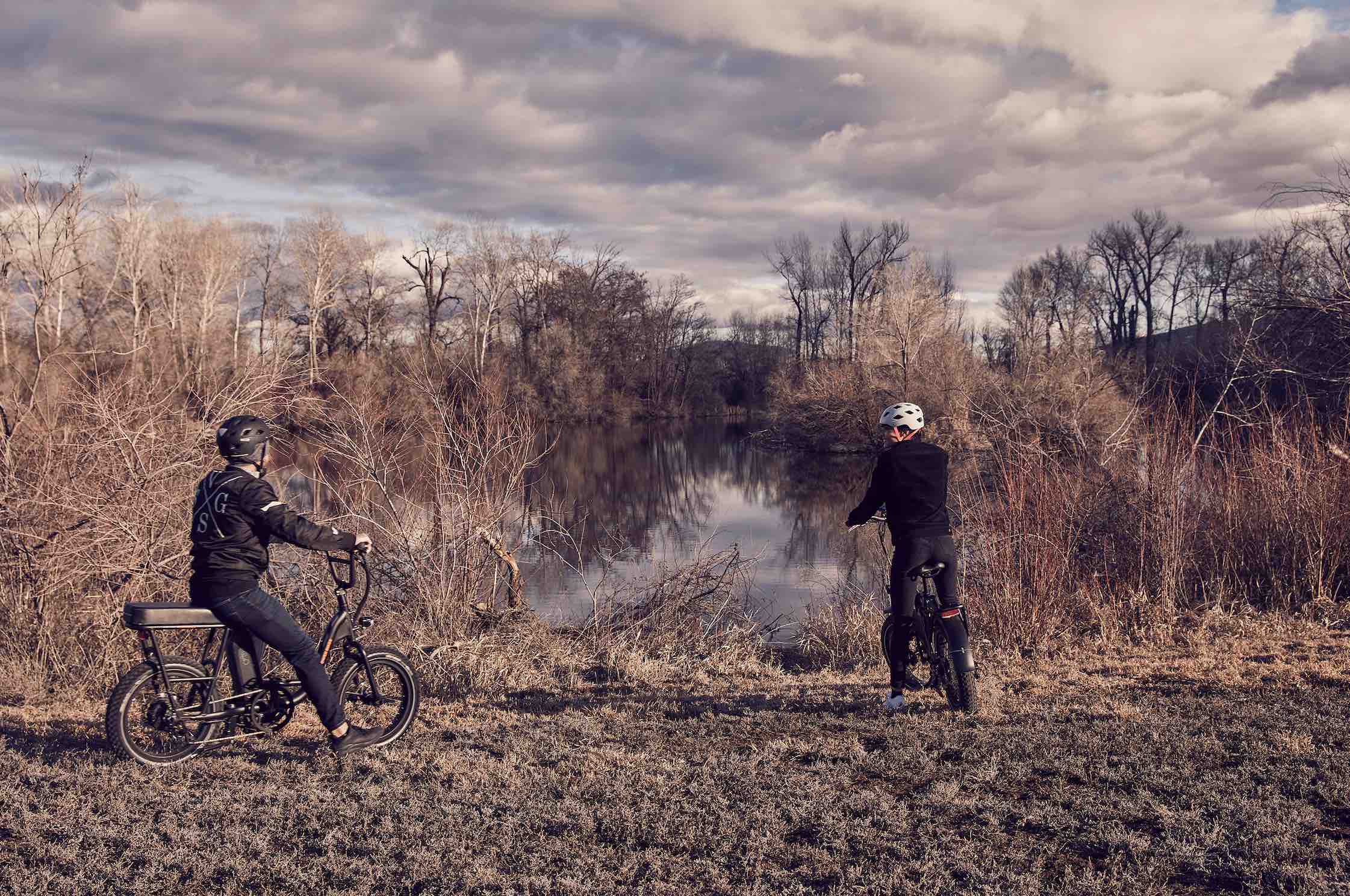 A man and woman ride their electric bikes to a pond.