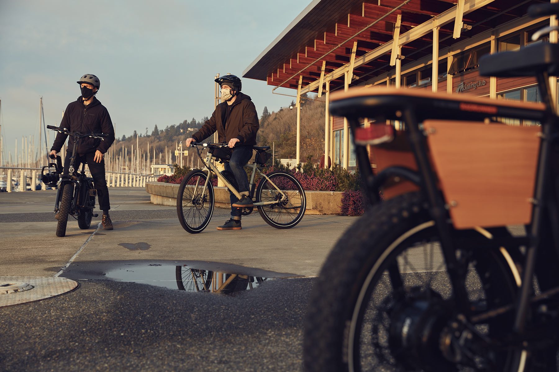 Three riders are on their electric bikes near a puddle