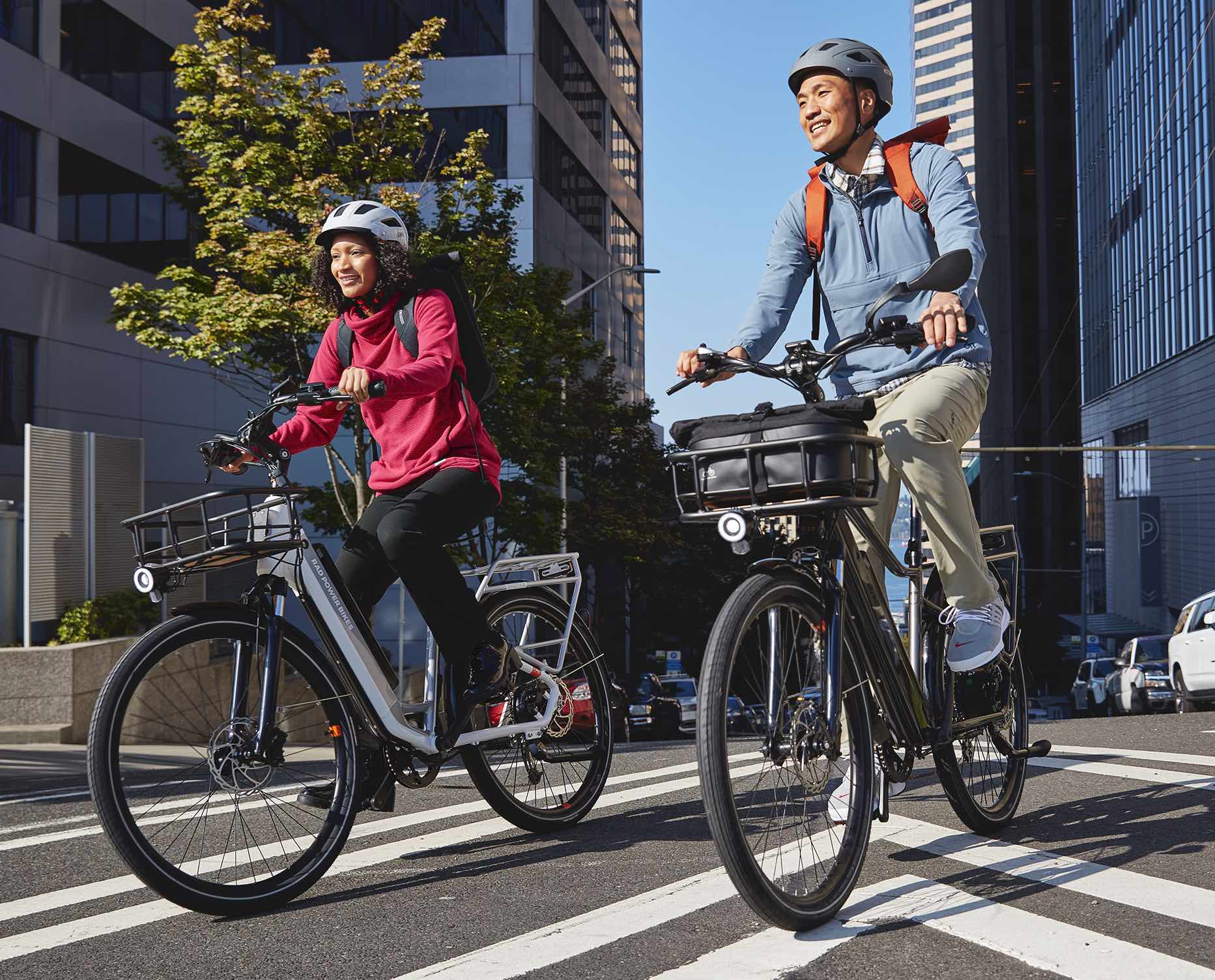 Two riders ride their RadCity electric commuter bikes through city streets.